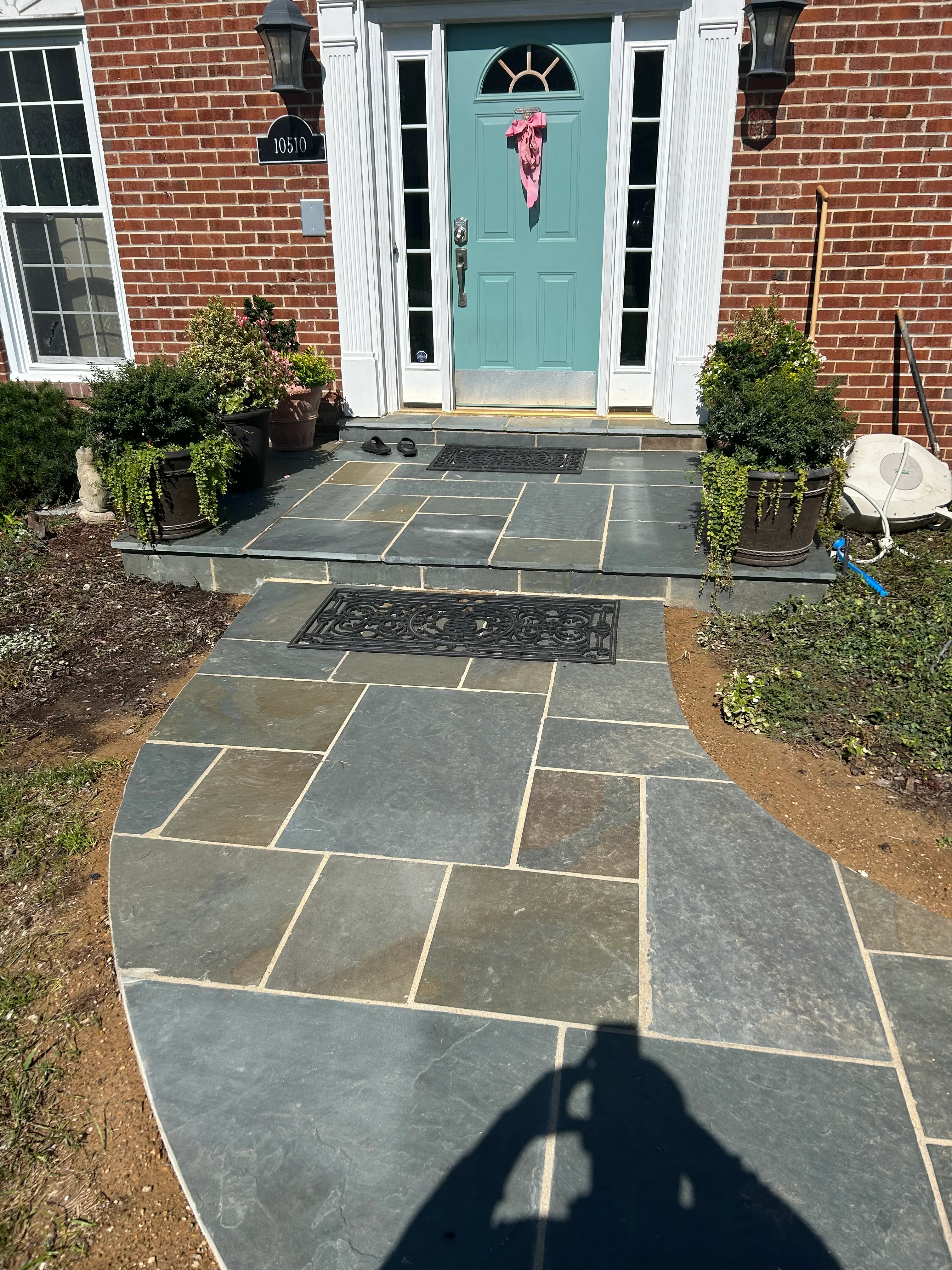 Slate flagstone patio and walkway with curved design leading to turquoise front door