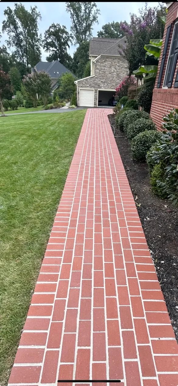 Red brick herringbone walkway leading to residential garage with landscaping