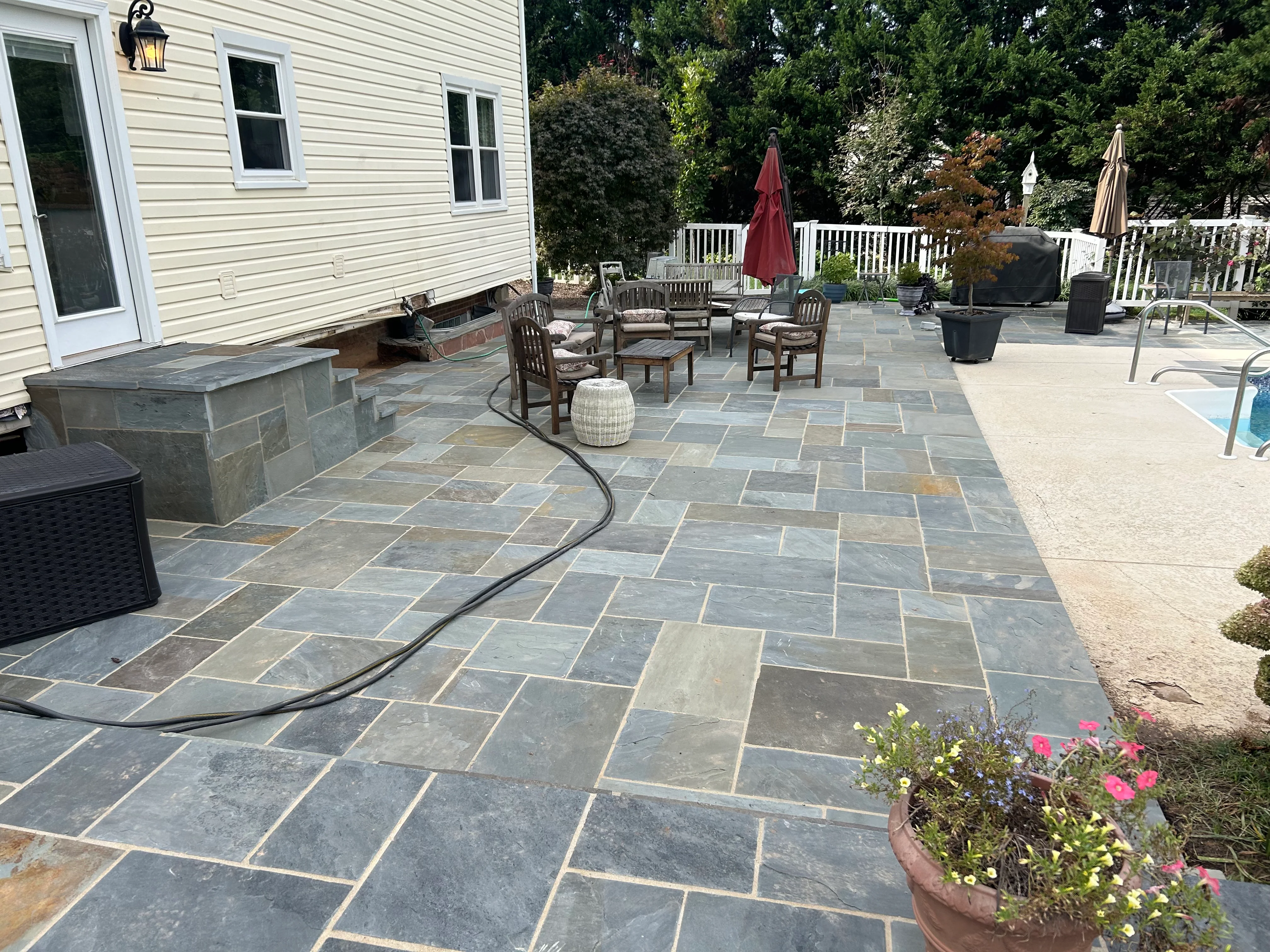 Large bluestone patio with ashlar pattern, stone seating wall, and outdoor furniture