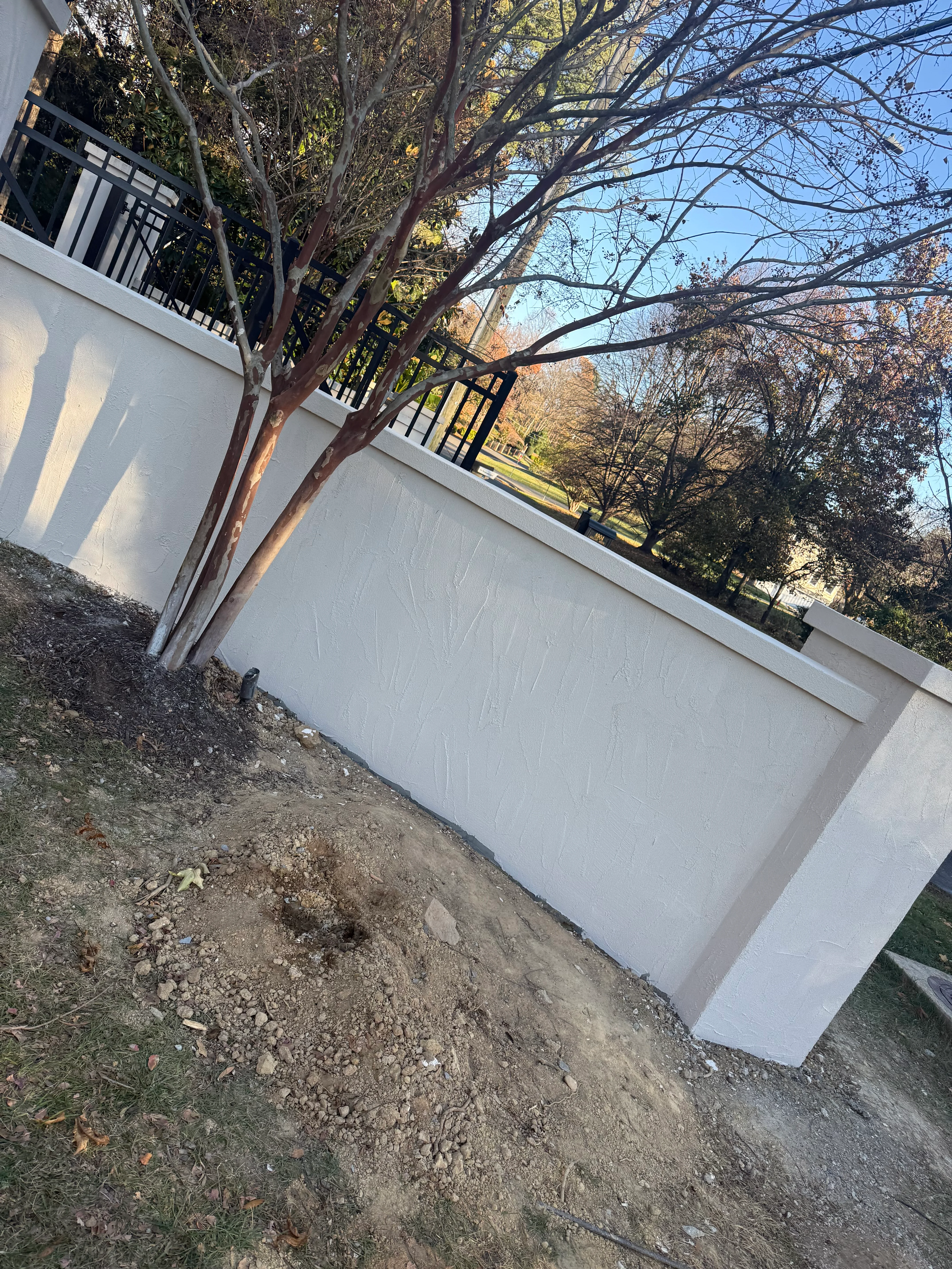 White retaining wall with black metal railing along residential property in Fairfax
