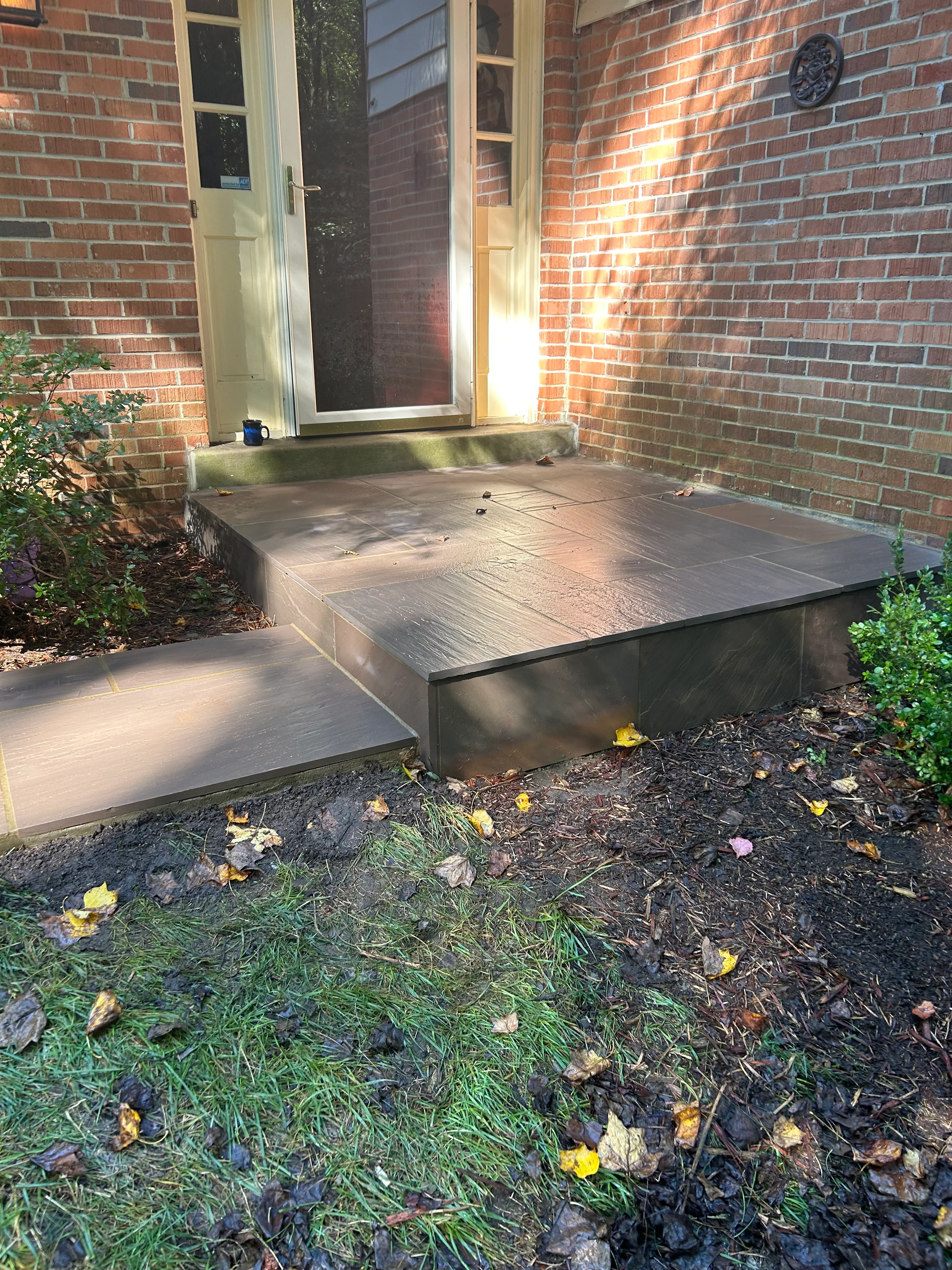 Concrete entryway platform with two levels at brick home entrance