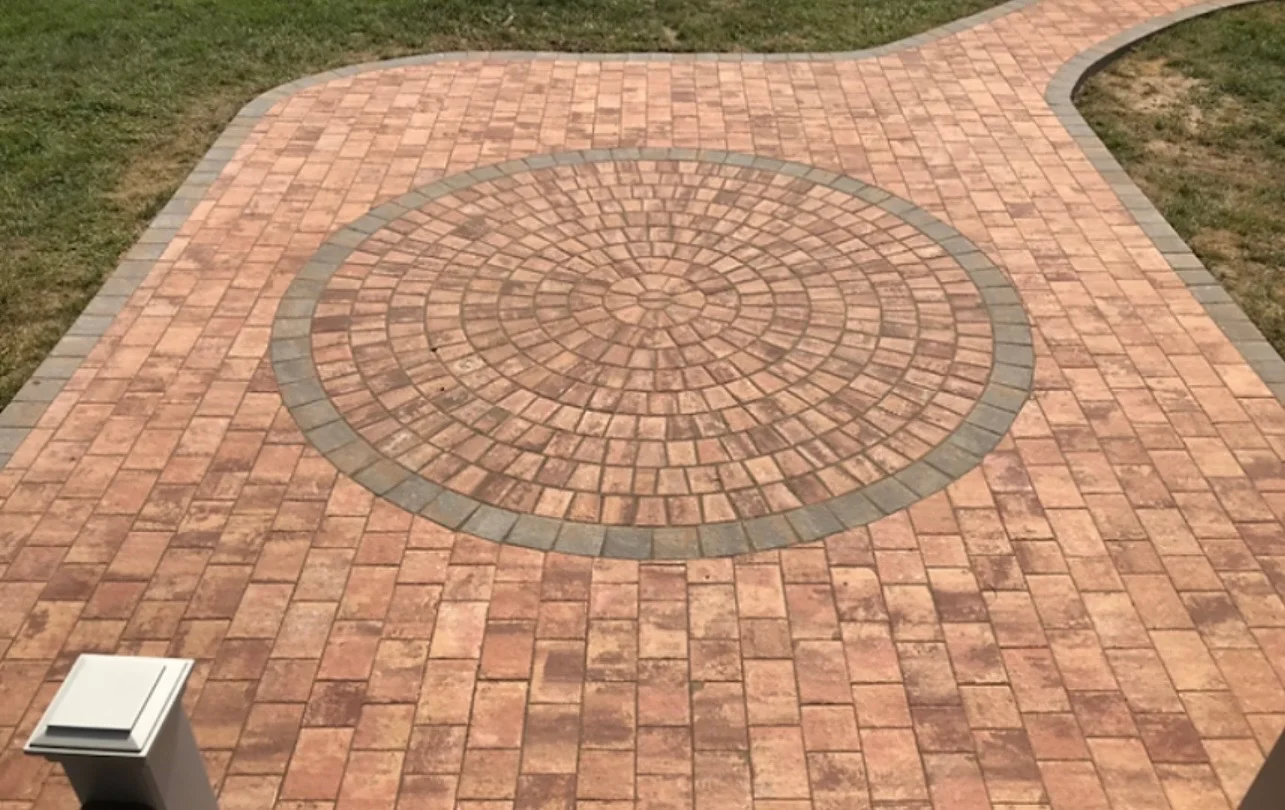 Circular clay brick patio with radial gray paver pattern and curved edges