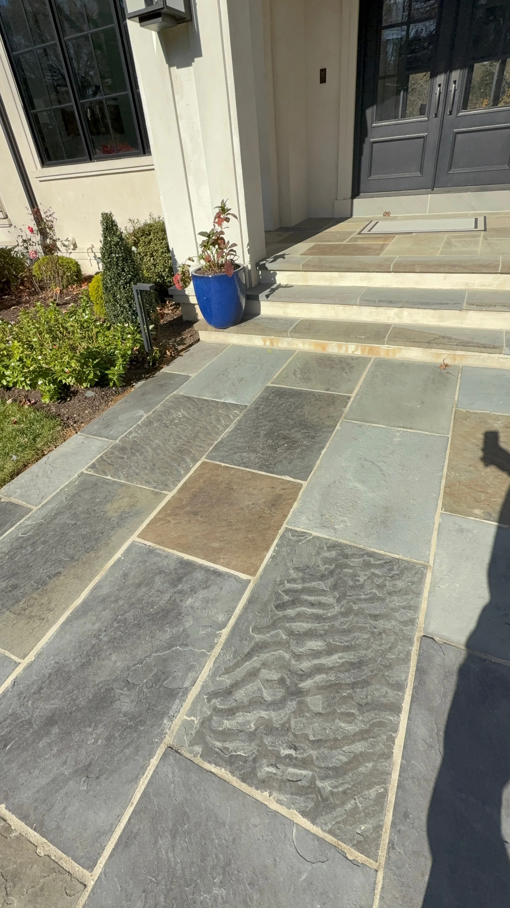 Natural slate patio with mixed-tone stone tiles and light mortar joints leading to home entrance