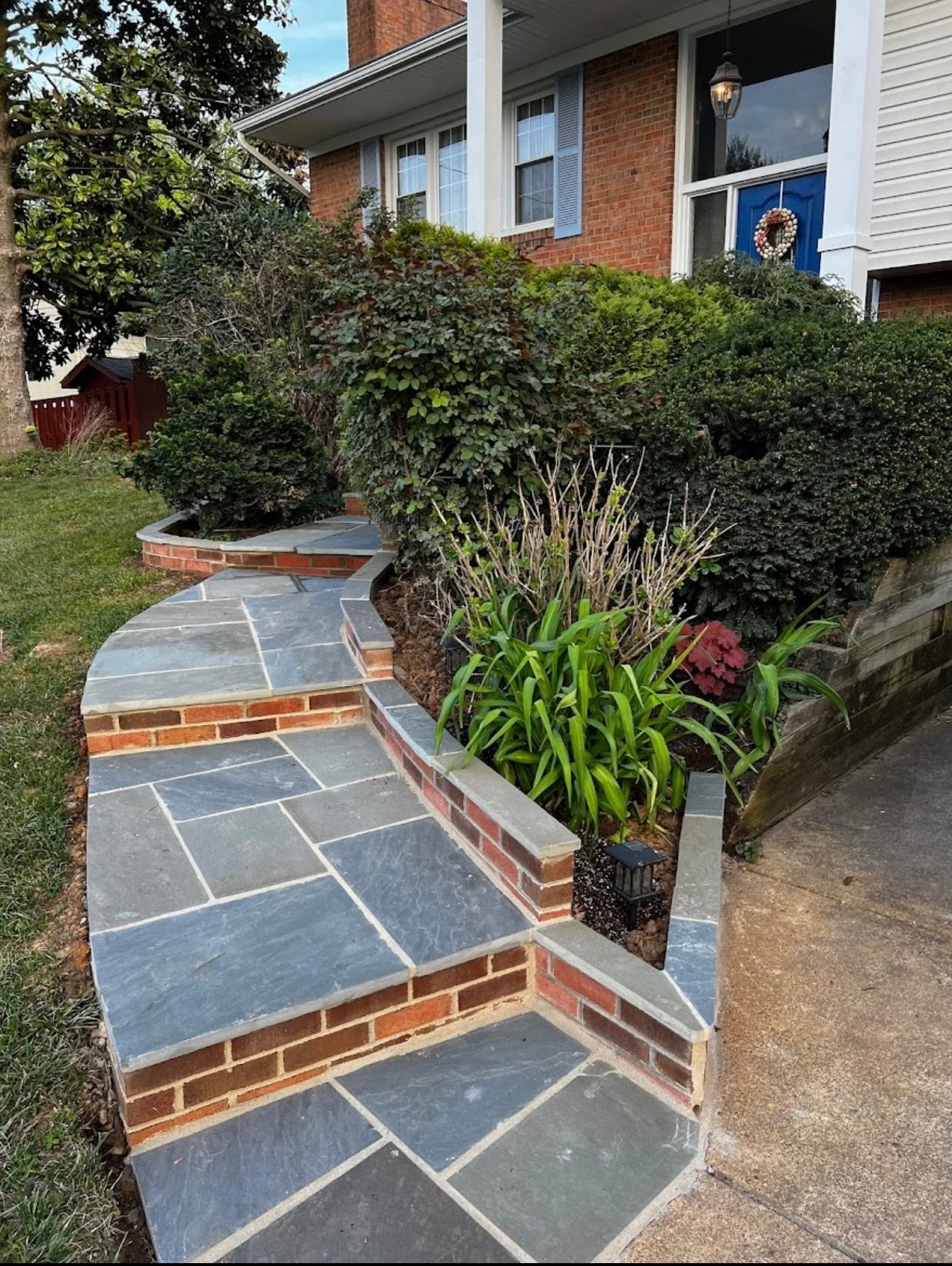 Slate flagstone walkway with brick borders leading to brick home entrance