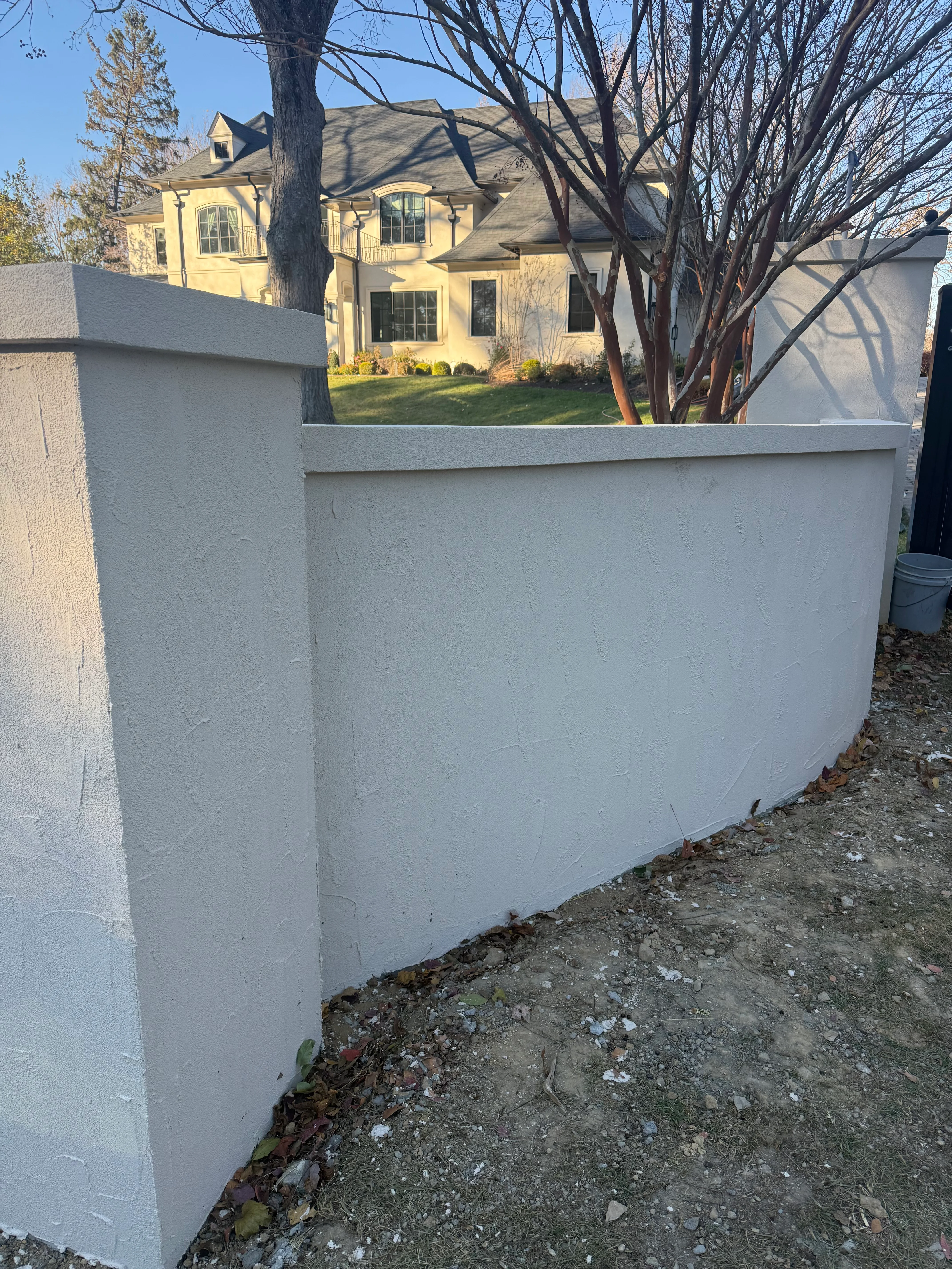 Light gray concrete retaining wall with curved design bordering residential property