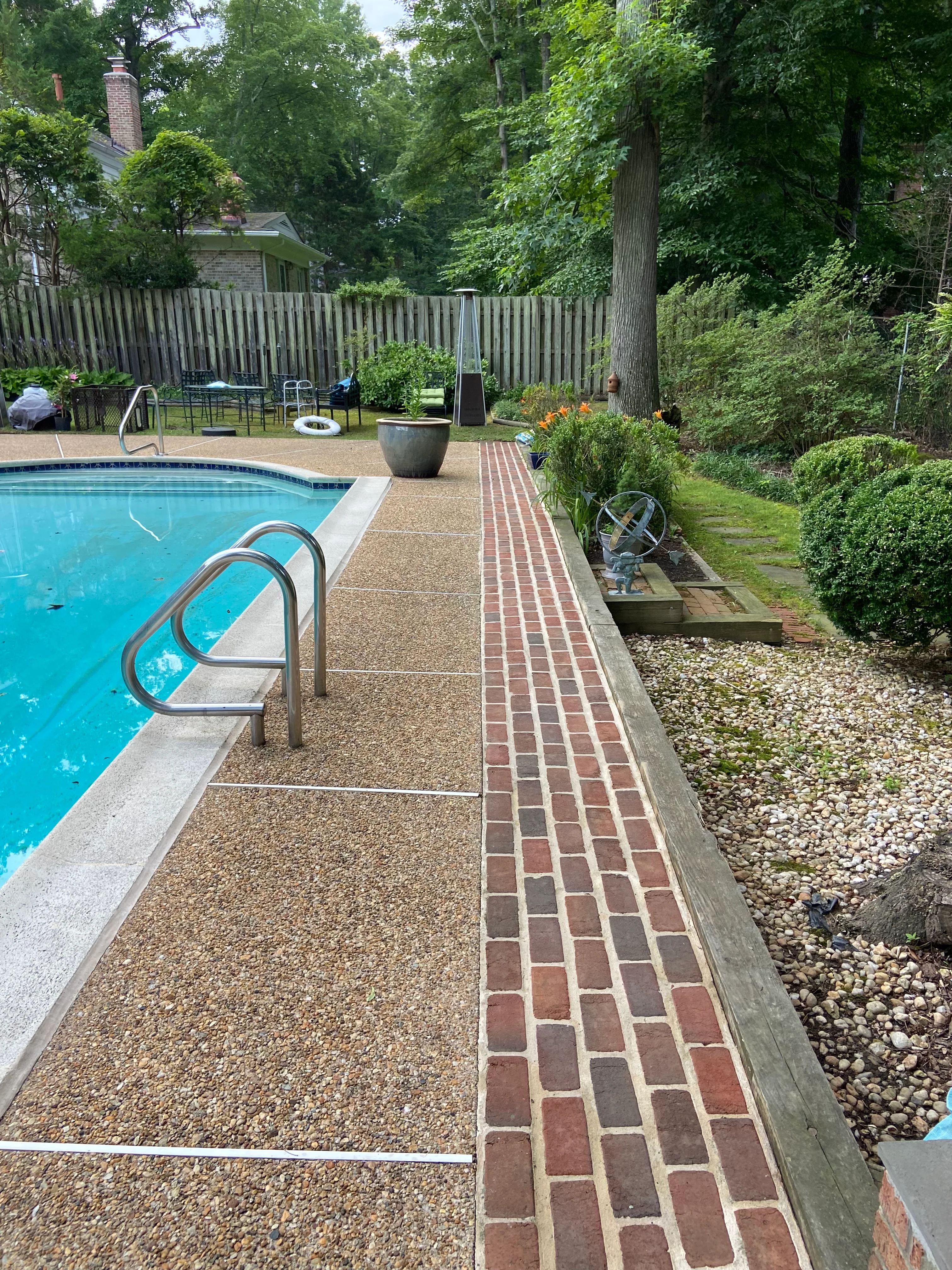 Pool deck with brick paver pathway and aggregate patio surface