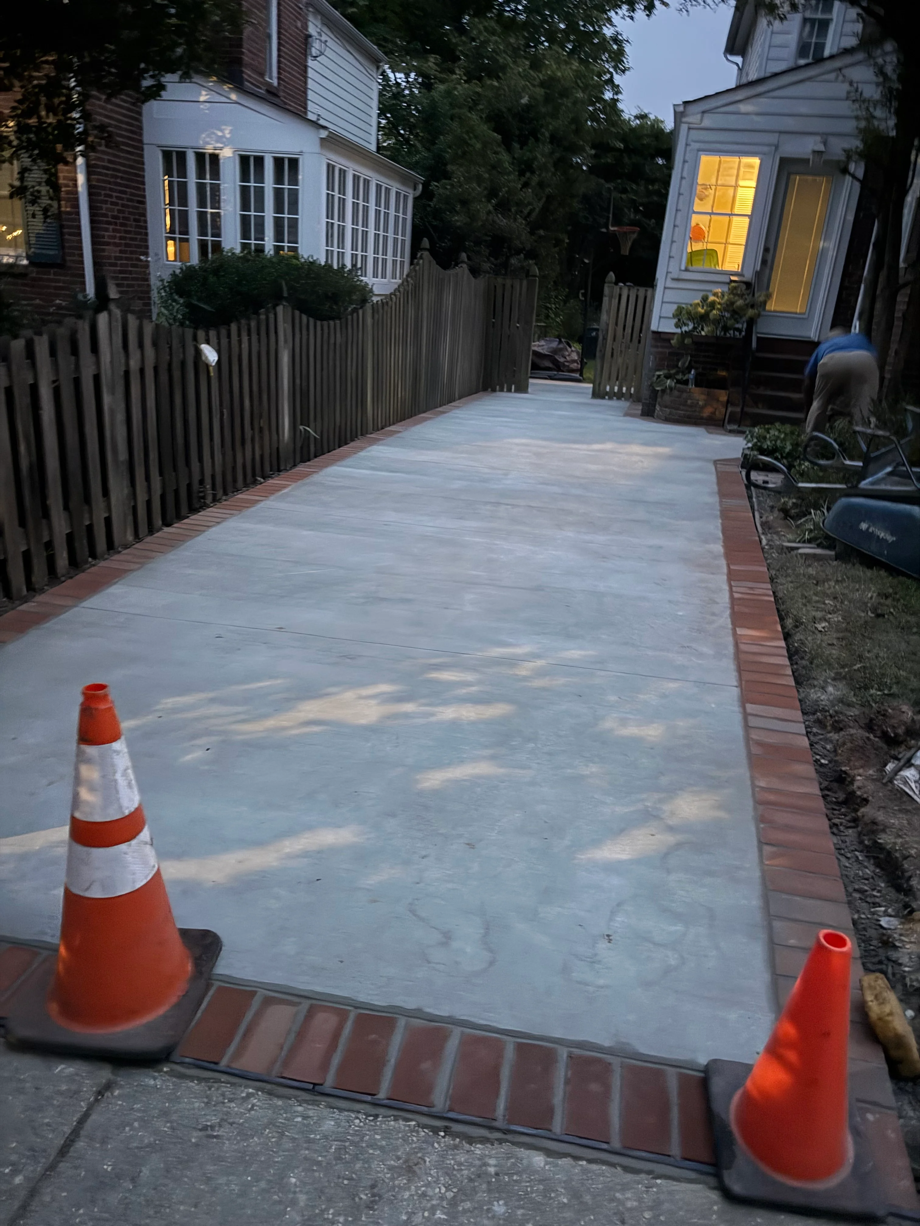 Newly installed concrete patio with brick edging in residential backyard