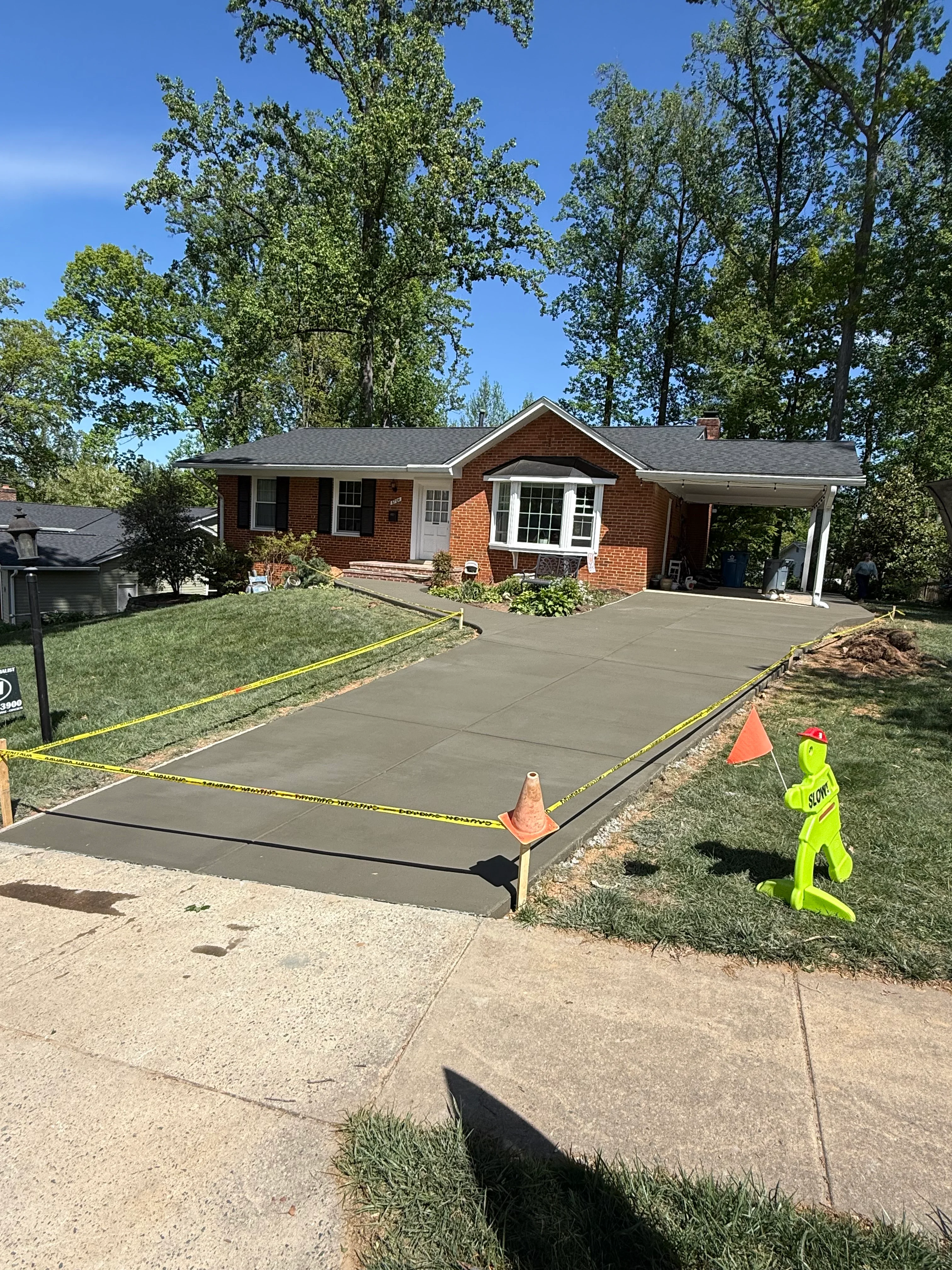 Newly poured concrete driveway with caution tape at brick home in Fairfax